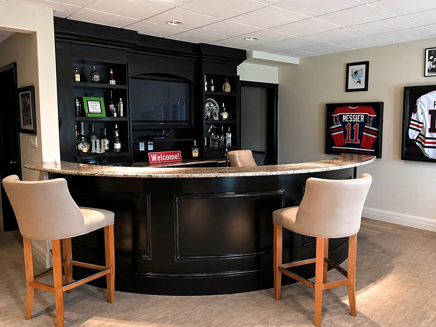 Curved black basement bar with sports memorabilia
