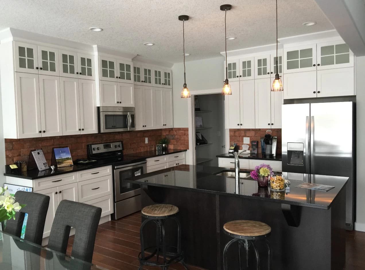 White kitchen with brick backsplash and dark island