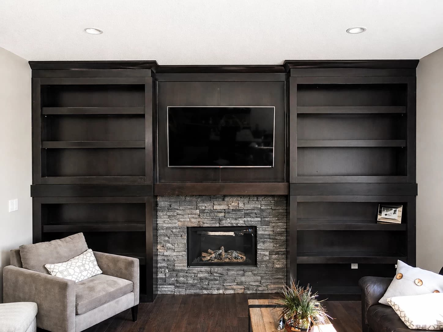 Dark espresso entertainment centre with stacked stone fireplace and built-in shelving