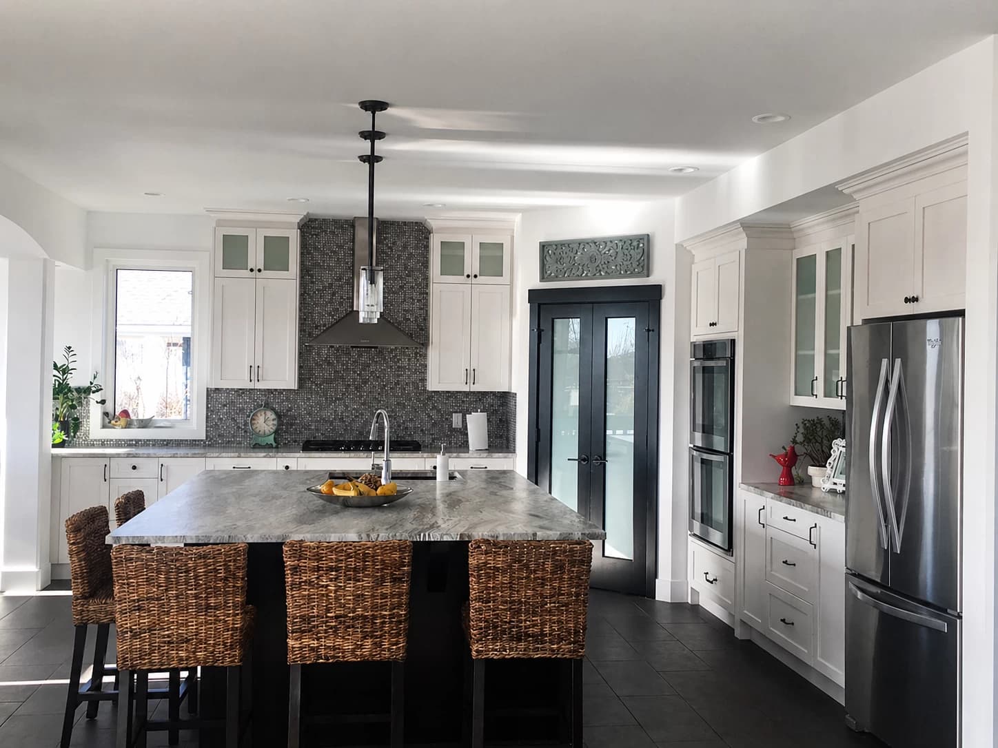 White shaker kitchen with patterned blue backsplash and woven rattan island