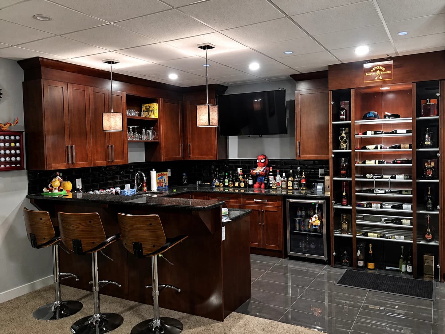 Dark cherry basement bar with cabinetry, glass shelving, and bar stools