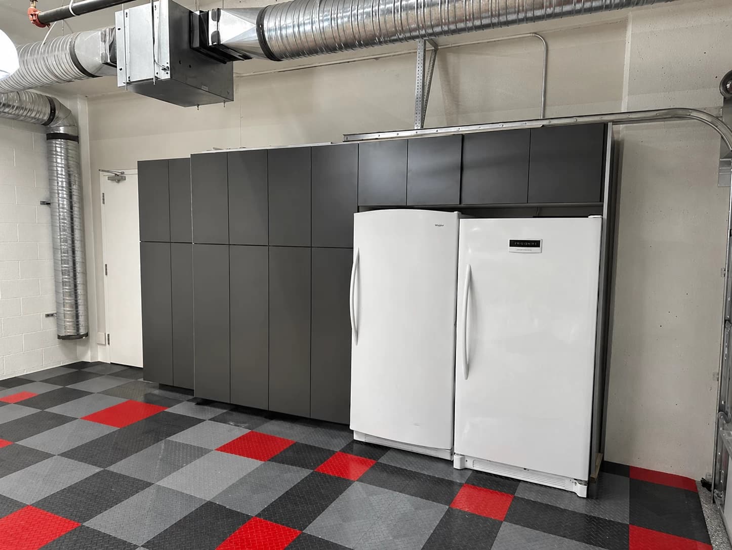 Grey garage storage cabinetry with white upright freezers