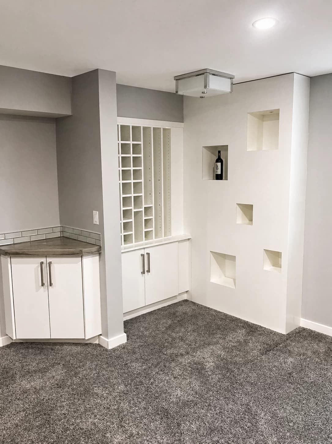 White basement wine cubby with accent niches and base cabinetry