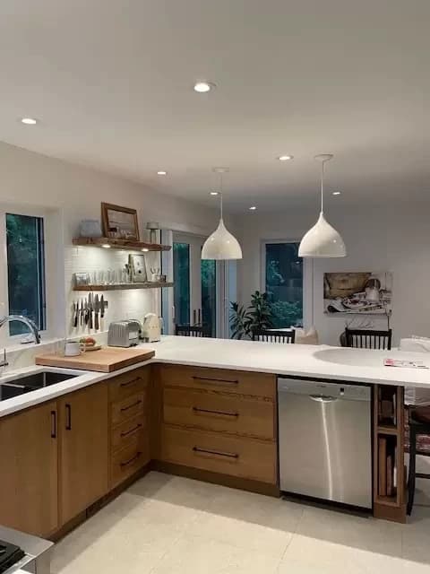 Light oak kitchen with floating shelves and open pass-through to dining area