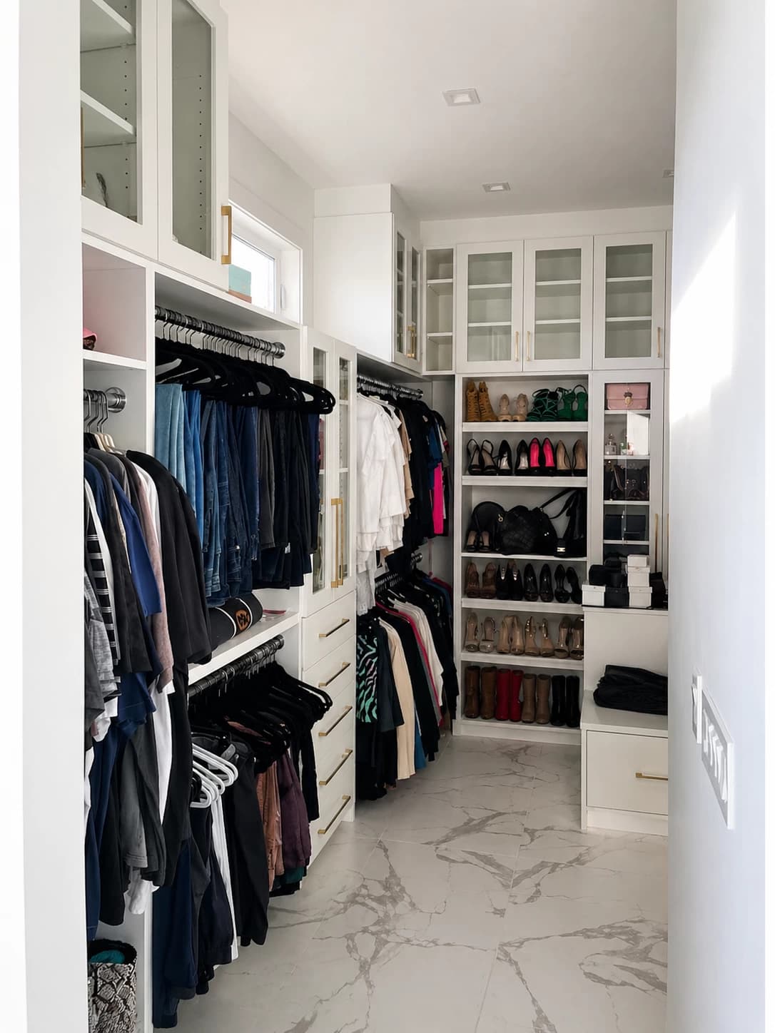 White walk-in closet with marble floor, shoe display, and hanging wardrobe sections